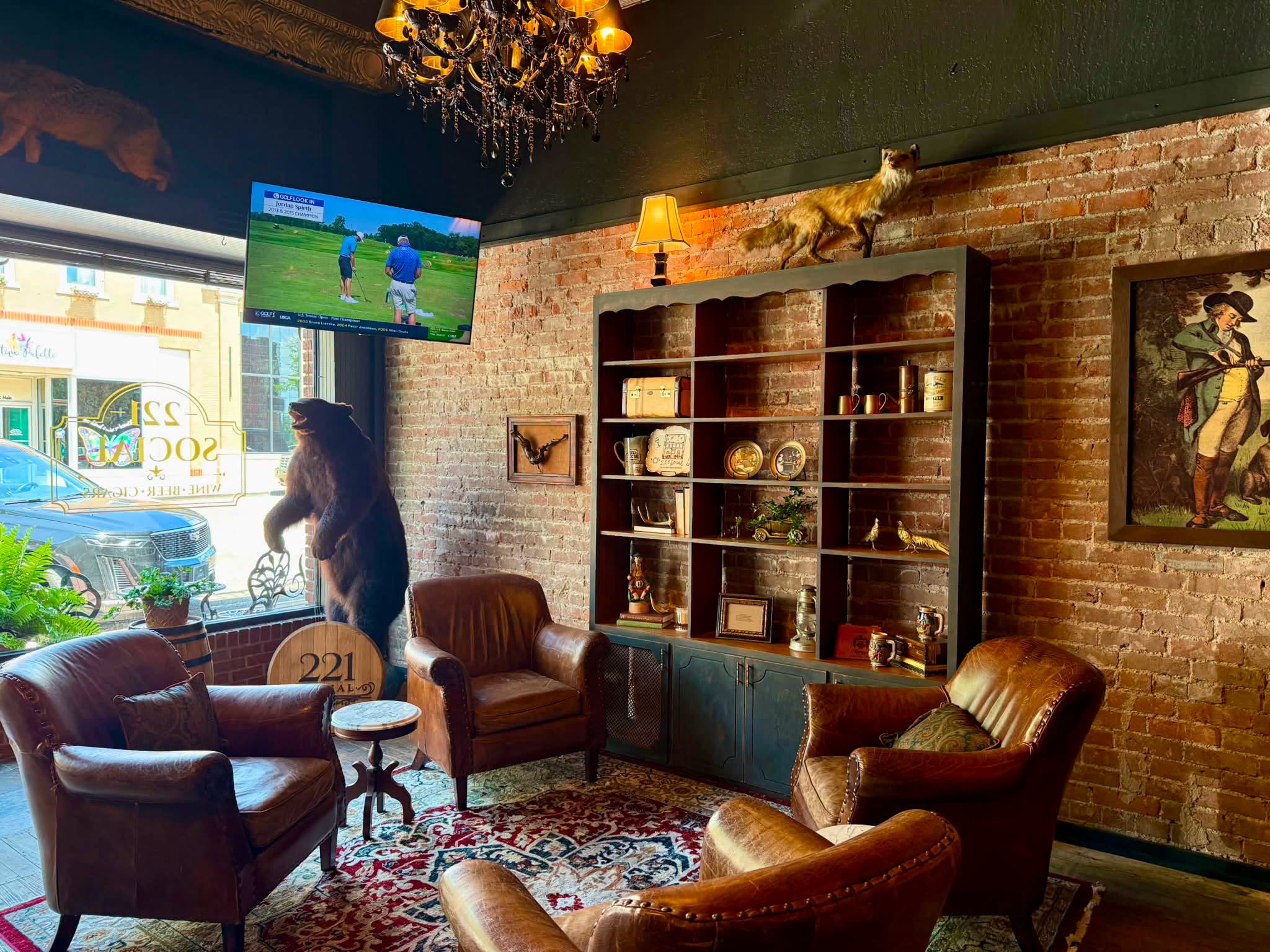 Leather armchairs on a Persian rug beside exposed brick and an antique bookcase